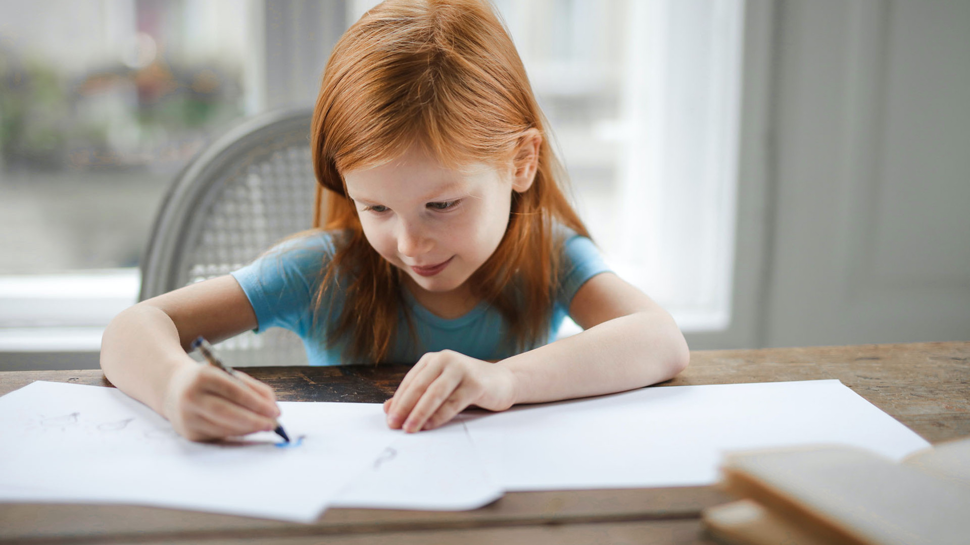 Jeune fille qui dessine avec des crayons à colorier.